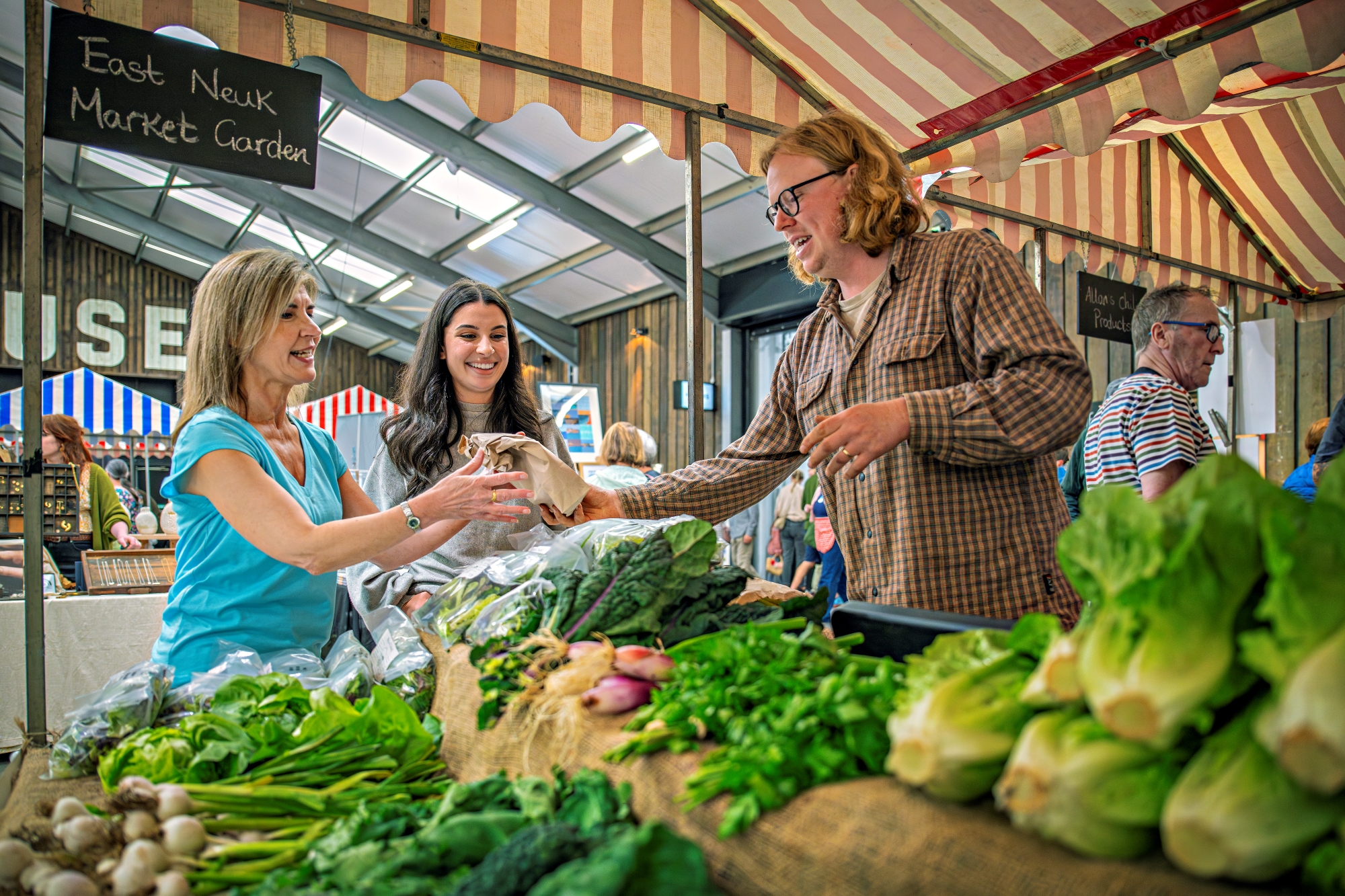 People buying and selling at a vegetable stall at a market